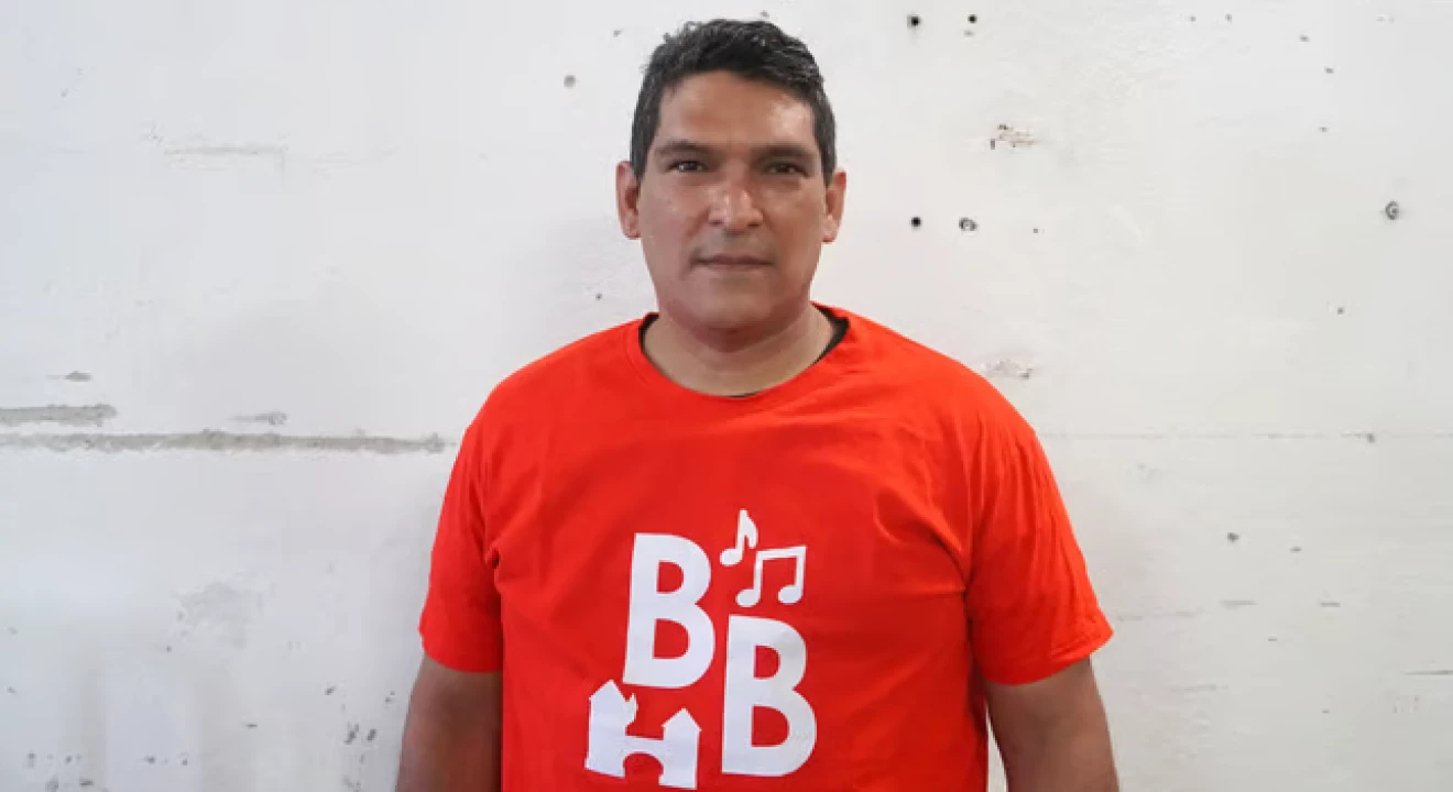 Portraitfoto von Mervin aus Venezuela, er trägt ein rotes T-Shirt von BrugglynBeats.